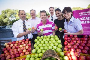 iga retailers join glenn mcgrath co-founder & president mcgrath foundation and steven cain, ceo of supermarkets, metcash with apples from south australia